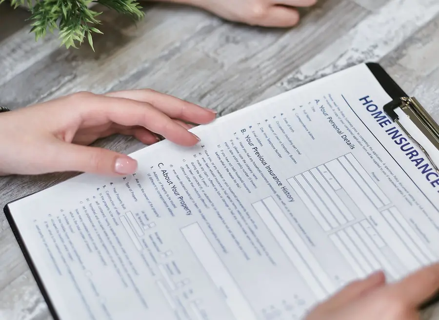 Homeowner holding a home insurance claim form on a clipboard
