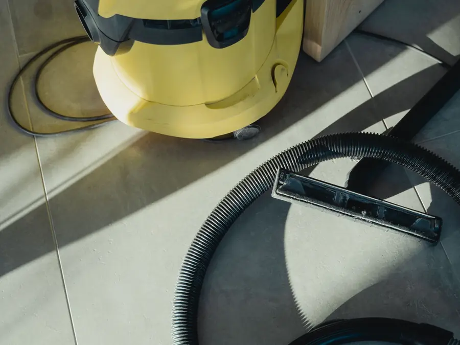Yellow extraction vacuum and hose sitting on a tile floor