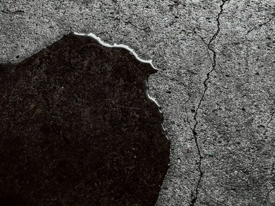 Wet patch spreading across cracked concrete